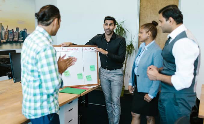 Team having a Retrospective standup in front of a Kanban board